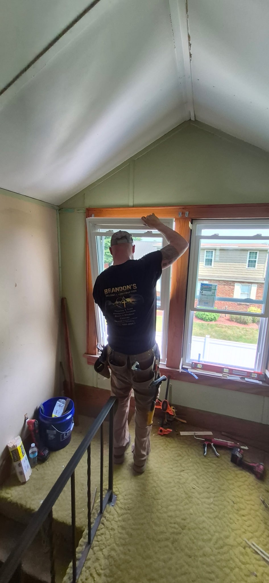 Technician on a ladder installing trim around a newly replaced window