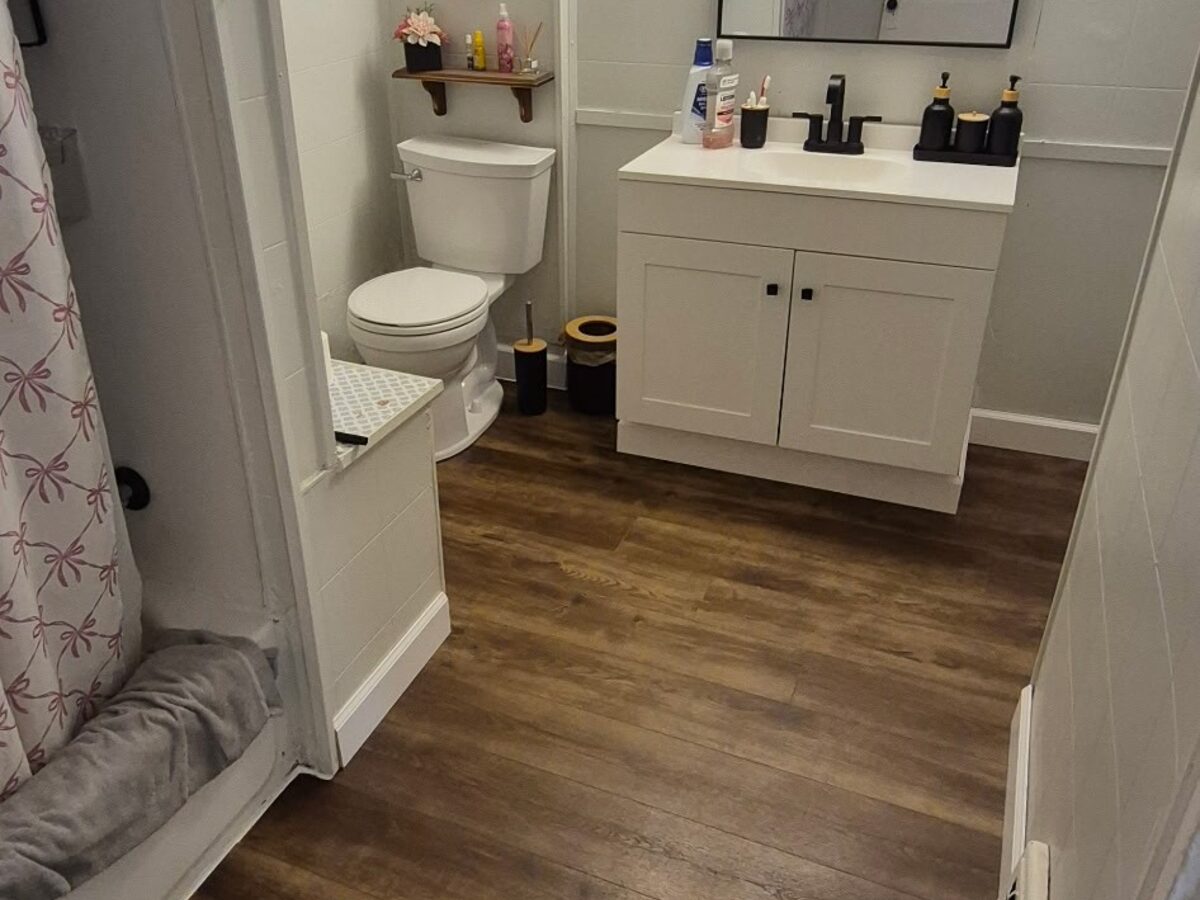 After: renovated bathroom with new flooring, vanity, and toilet